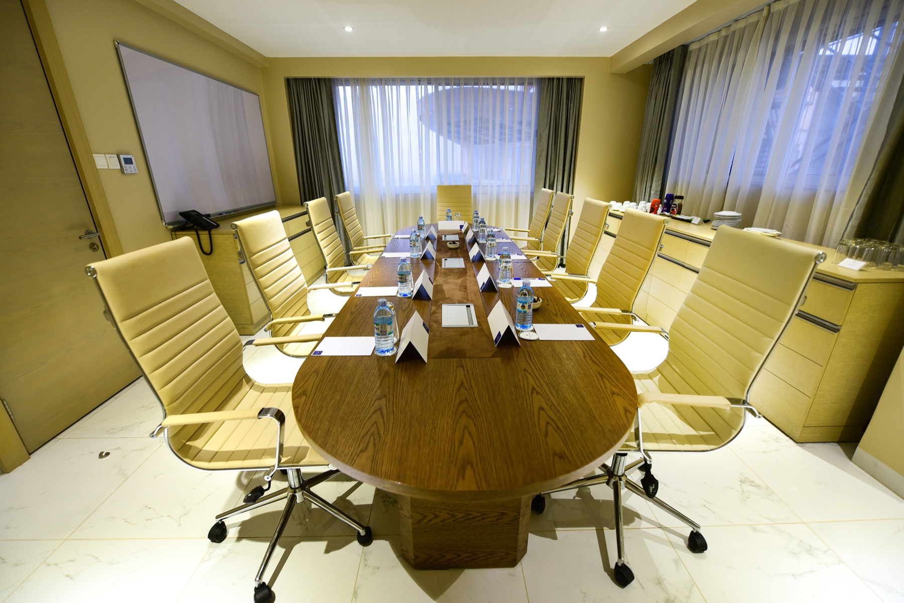 An elegant Skyz Hotel Kampala boardroom with an oval table and cream leather chairs