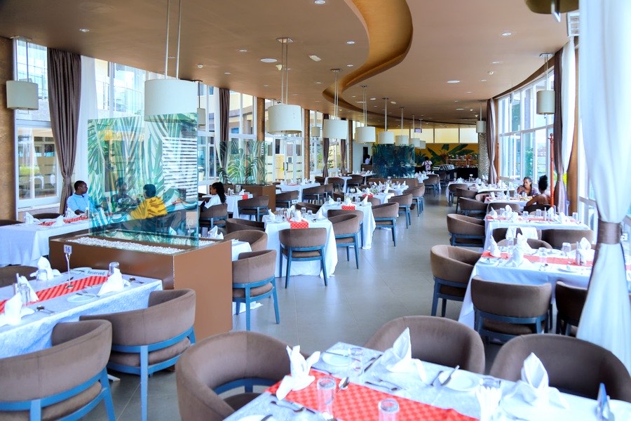 Chapter Two Restaurant tables laid with white cloths and red runners beside floor-to-ceiling windows