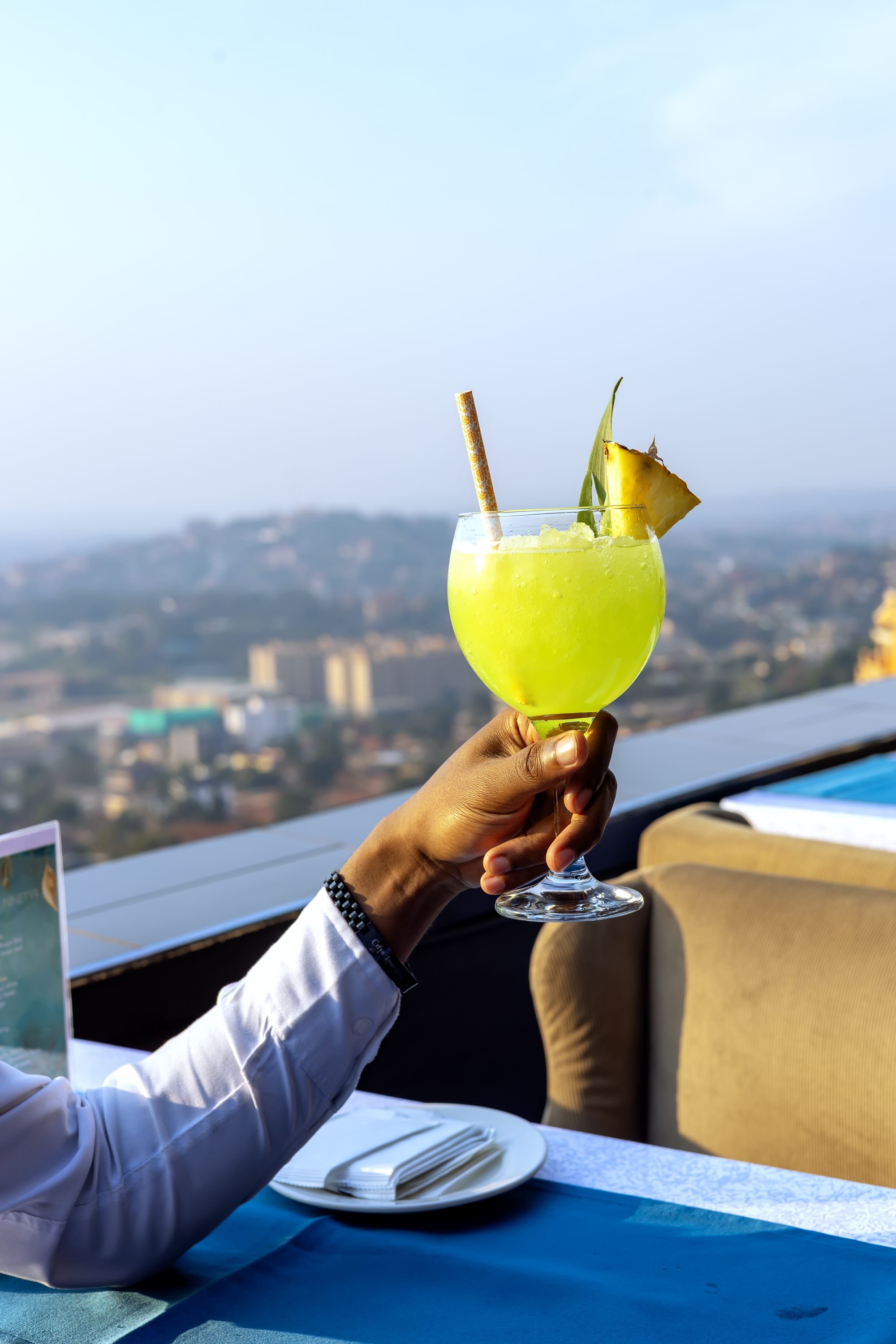 A crafted cocktail with a Kampala skyline view at Coffee 2 Cocktails