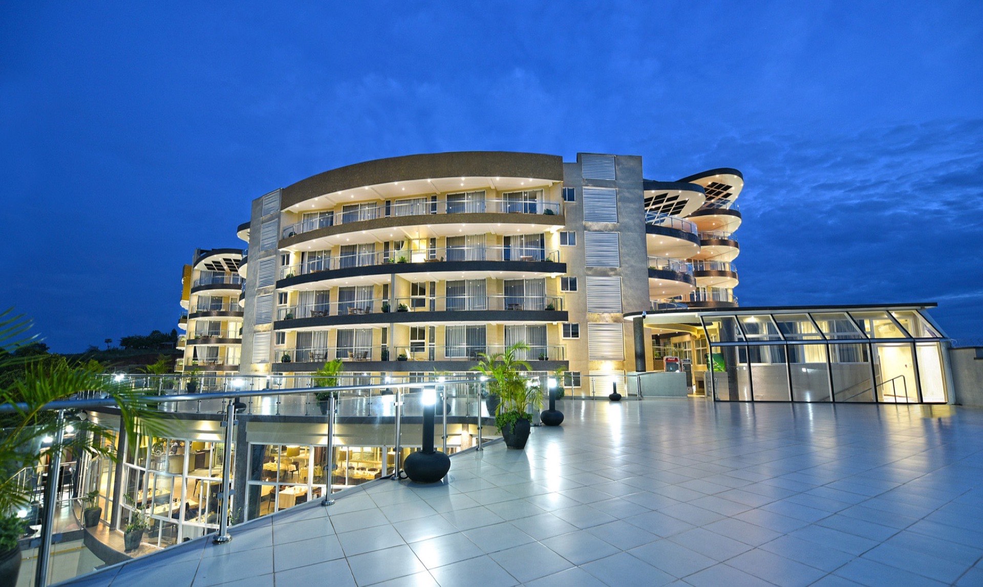 The curved facade of Skyz Hotel Kampala lit at dusk