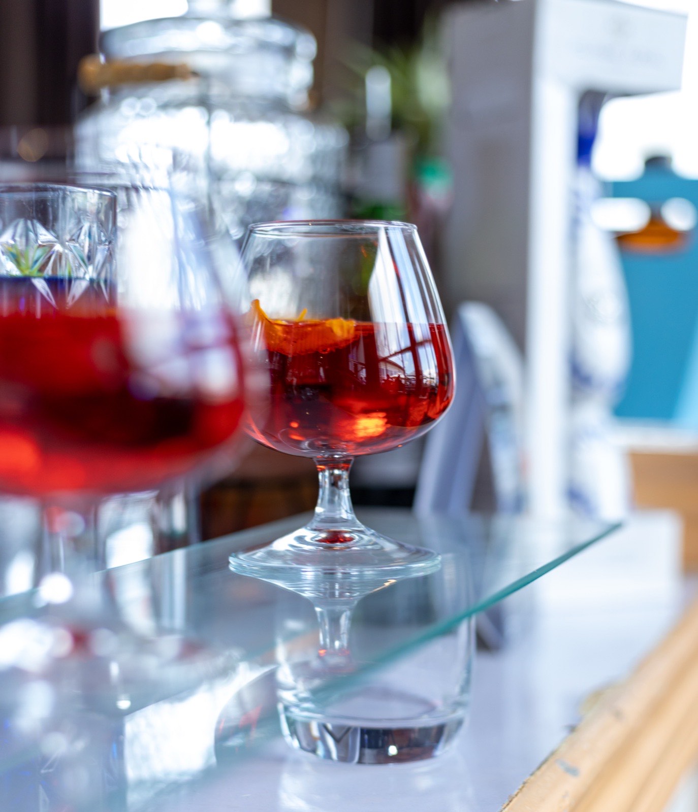 A close-up of a red cocktail garnished with orange peel on the bar counter at The Kampala Style Brunch, December 2024