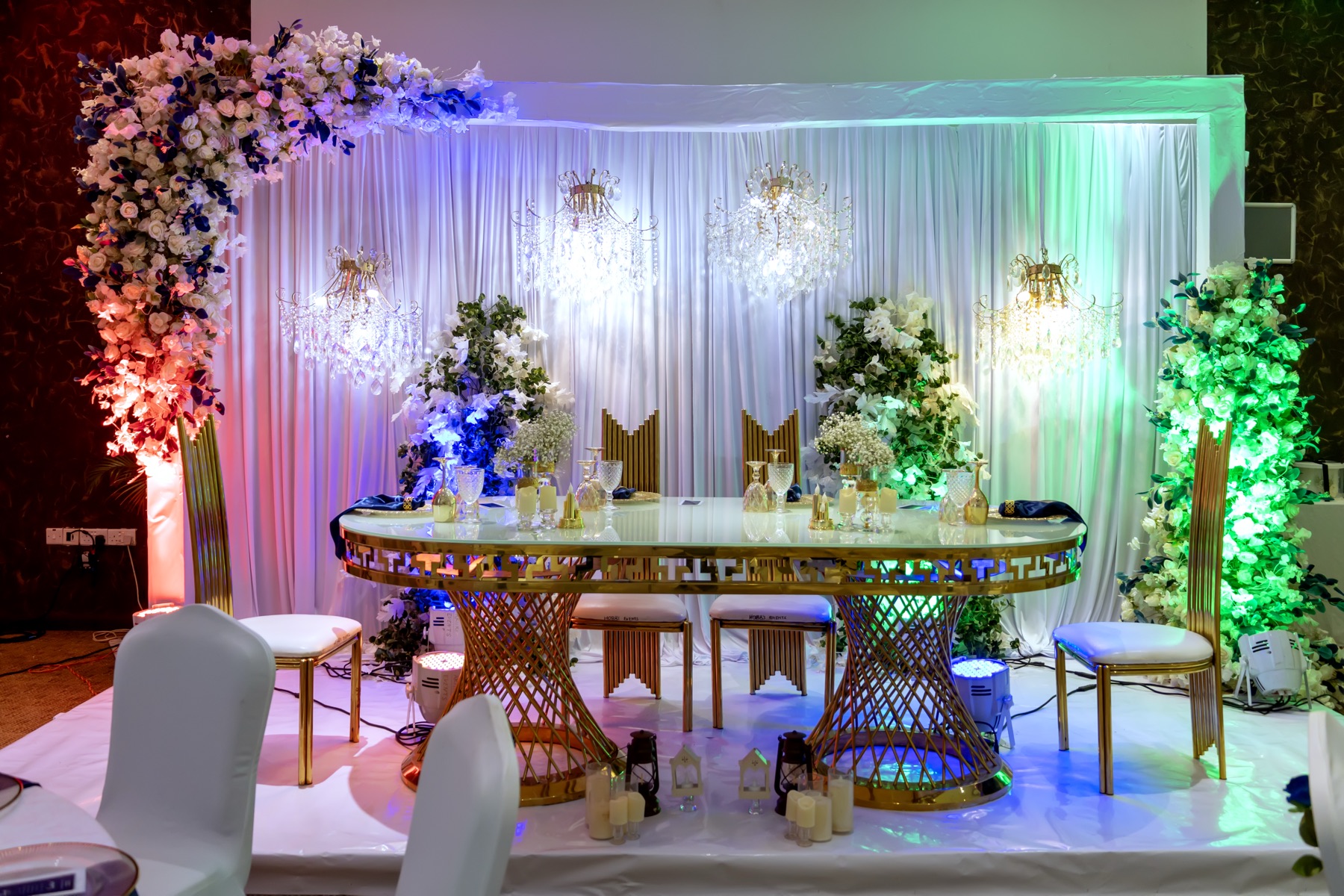 Kigali Hall styled with a floral arch, chandeliers and a decorated head table