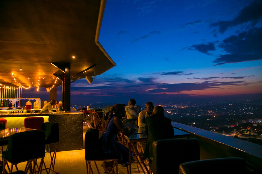 Ninety9 Rooftop bar and seating area with guests at blue hour, city lights beginning to twinkle below
