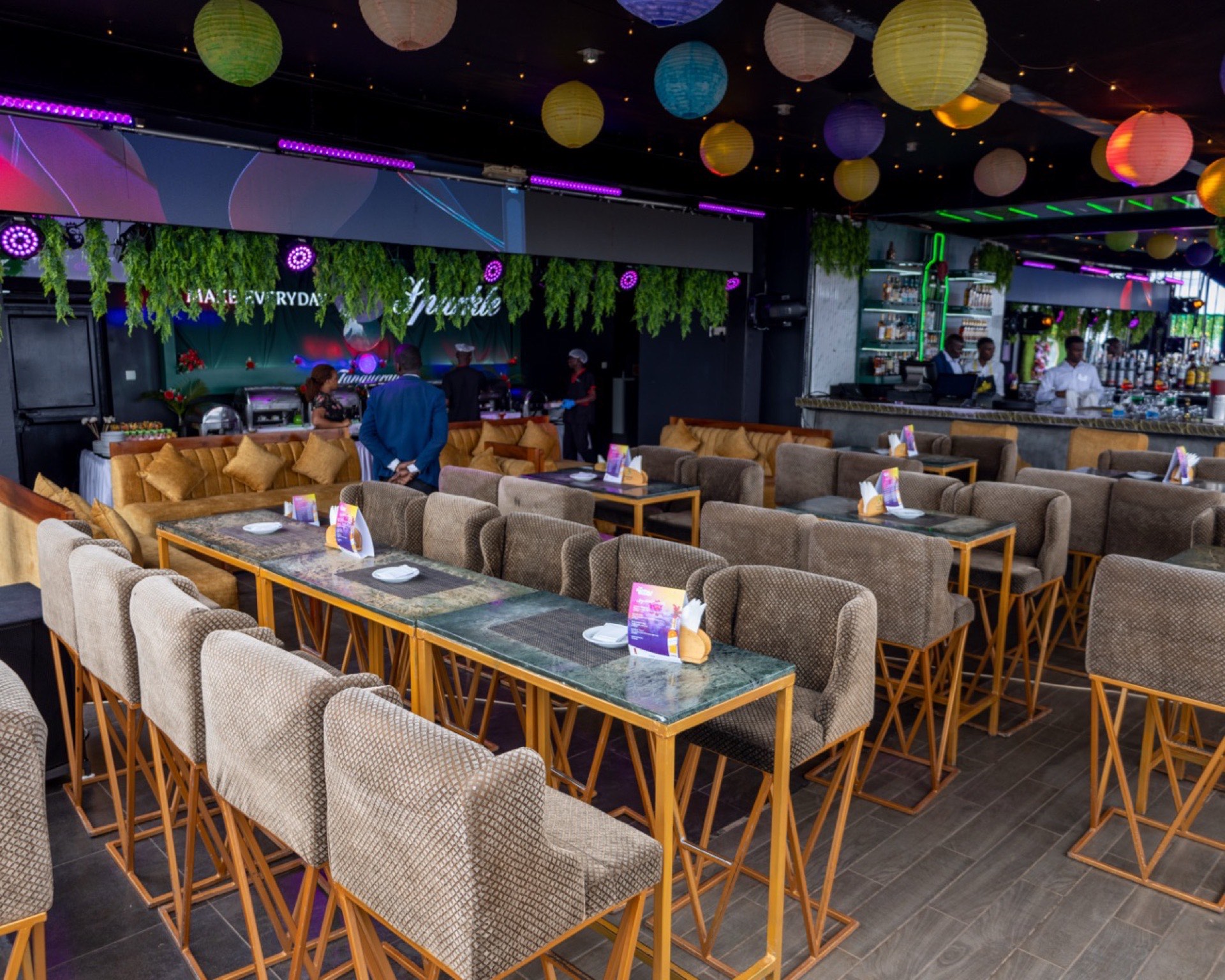 Ninety9 Rooftop's indoor lounge set up for an evening event, with paper lanterns, a stocked bar and lounge seating