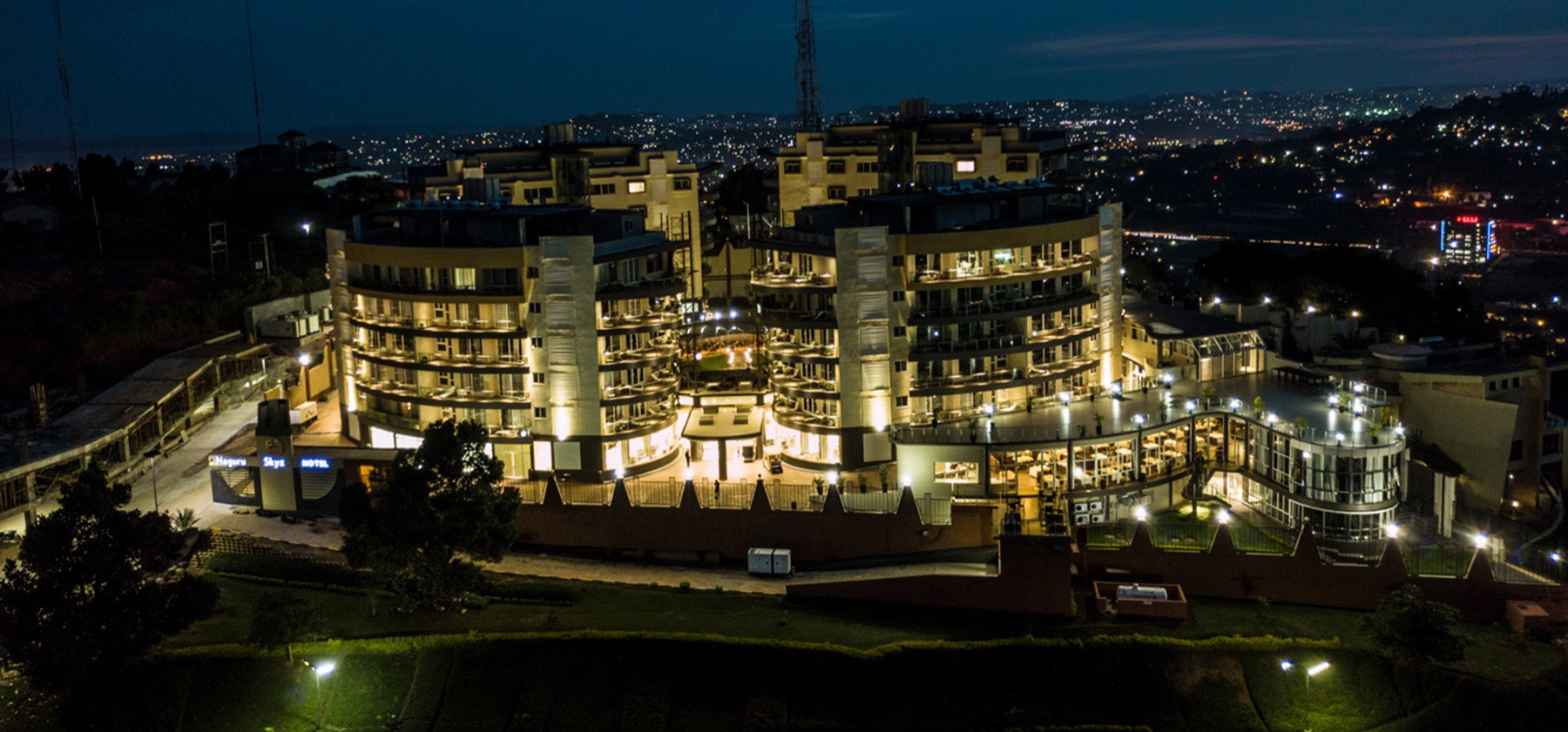 The Skyz sun-deck pool glowing at dusk beneath the curved hotel facade