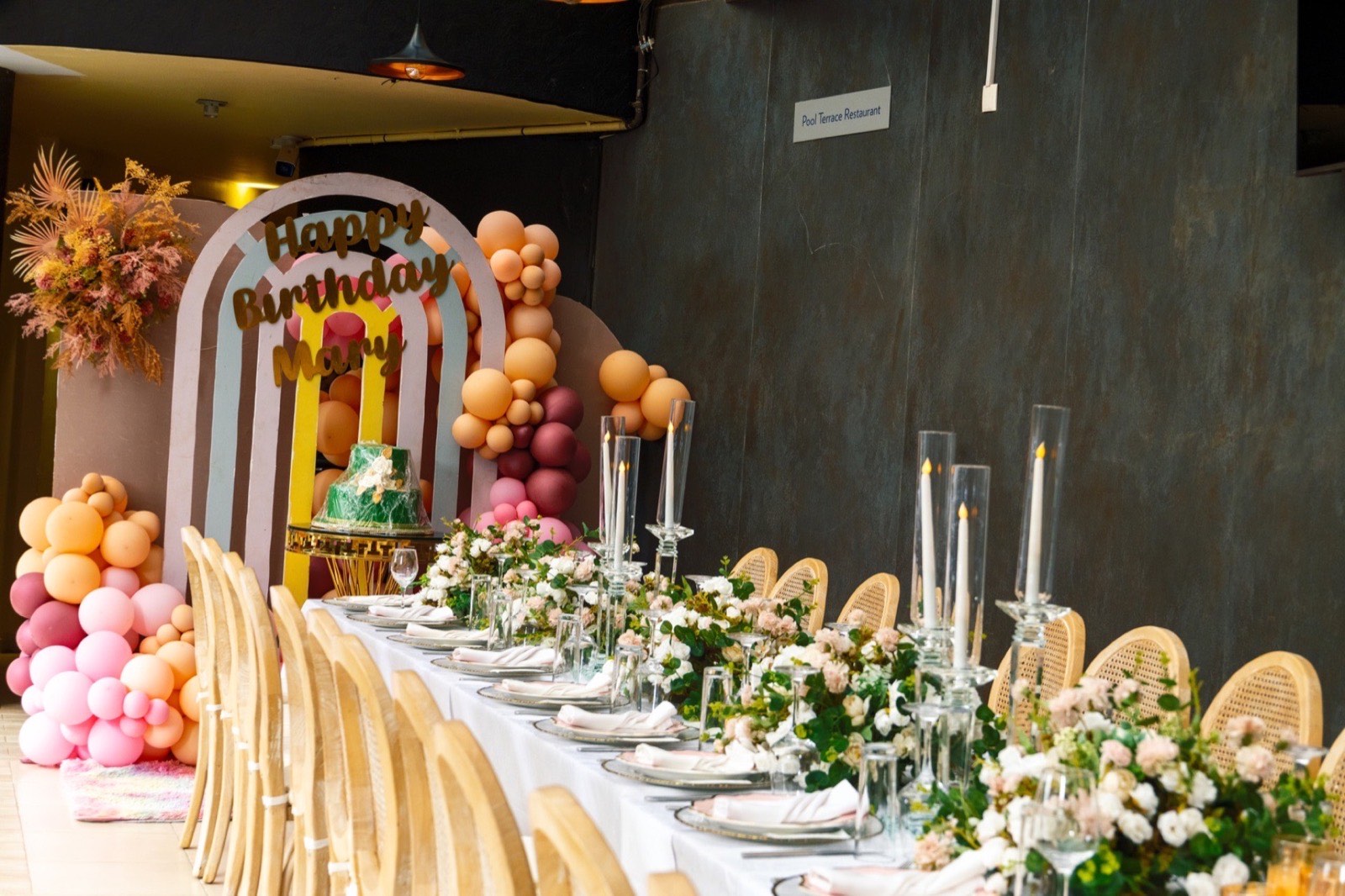 A private birthday celebration at the Tropicanna Poolside Restaurant, with a balloon arch and a floral table setting