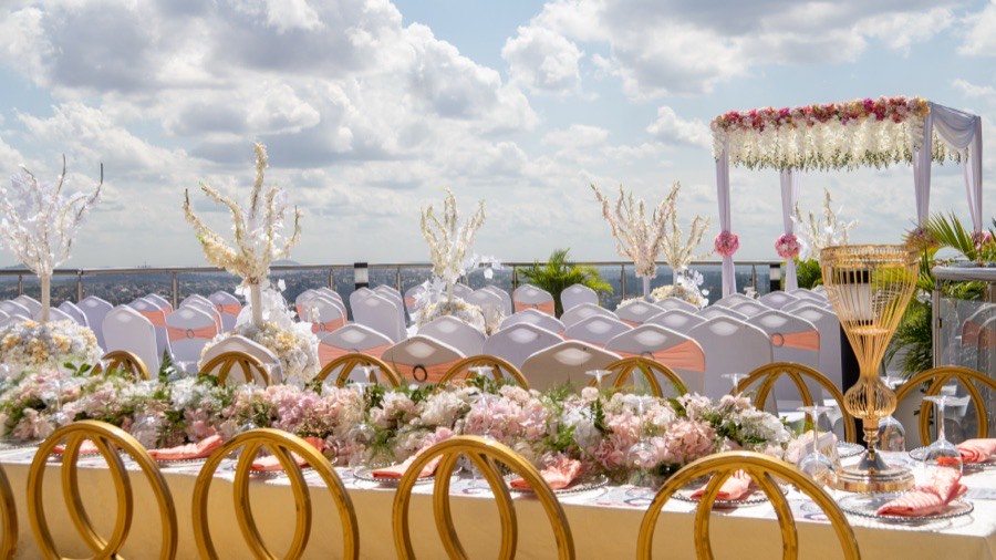 A wedding reception on Skyz Deck with a floral canopy, gold chairs and panoramic city views