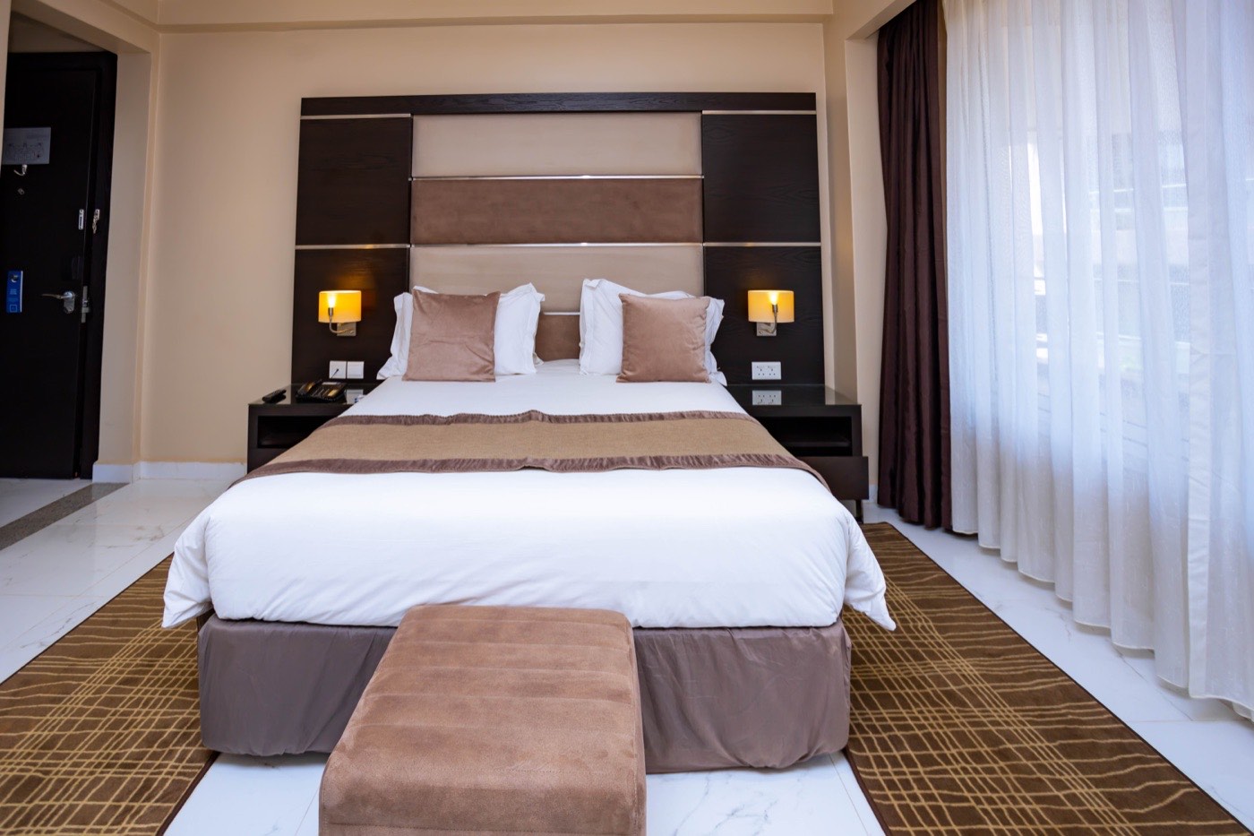 Close-up of the bed and padded headboard in a Standard Room at Skyz Hotel Kampala