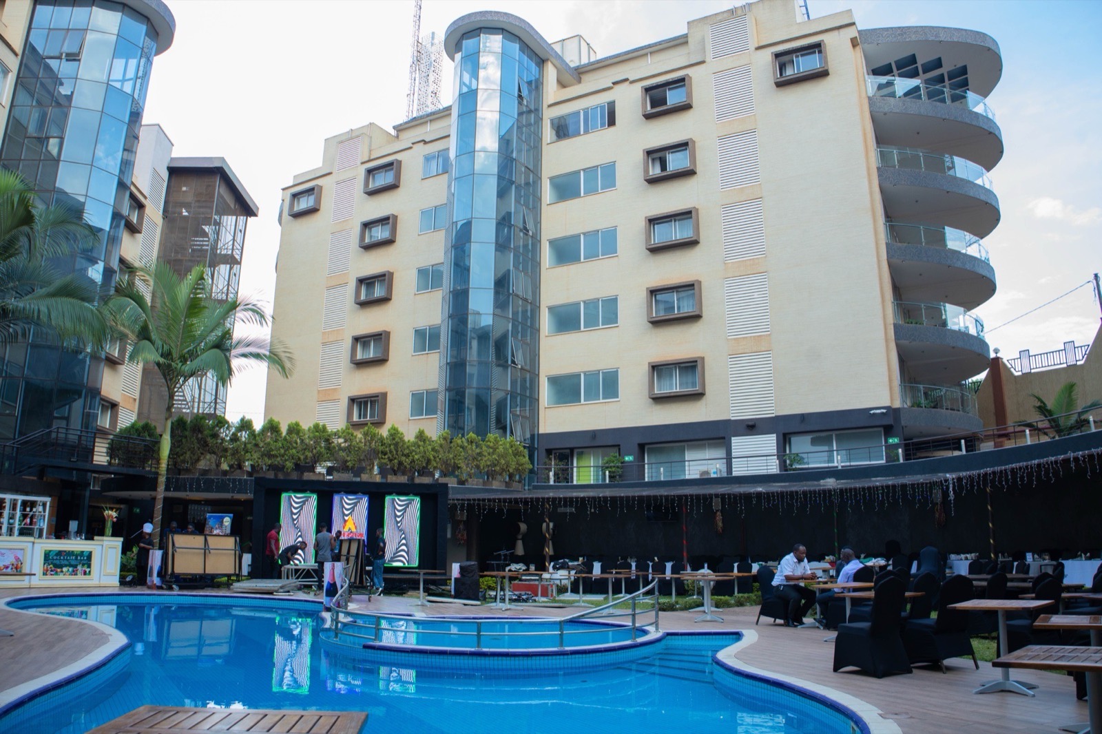 The pool deck at Skyz Hotel Kampala by day, with the Cocktail Bar, illuminated LED art screens and the hotel's residential tower behind
