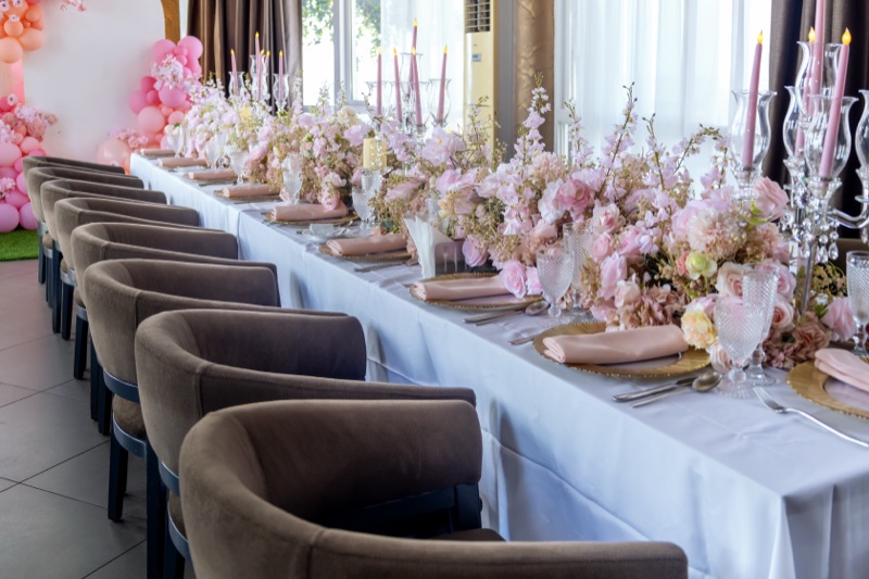 Close-up of a blush floral centrepiece with pink taper candles and rose-gold charger plates in the VIP Room at Skyz Hotel Kampala
