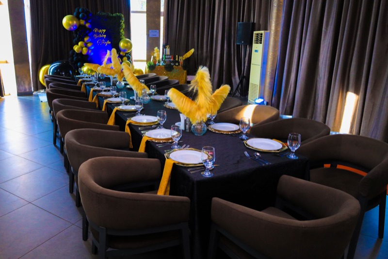 The VIP Room styled in black and gold for an evening celebration, with ostrich-feather centrepieces and gold charger plates at Skyz Hotel Kampala