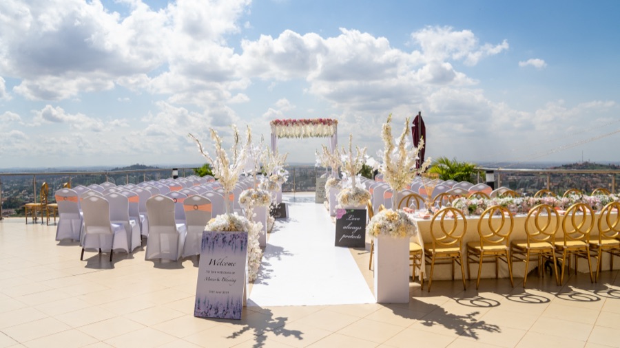 A rooftop wedding ceremony aisle with a floral arch overlooking the Kampala skyline